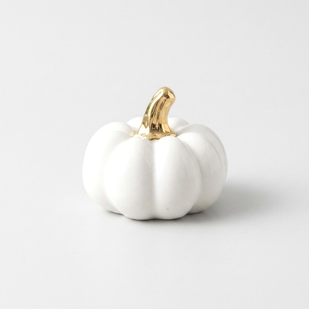 White ceramic pumpkin with a gold stem on a white background