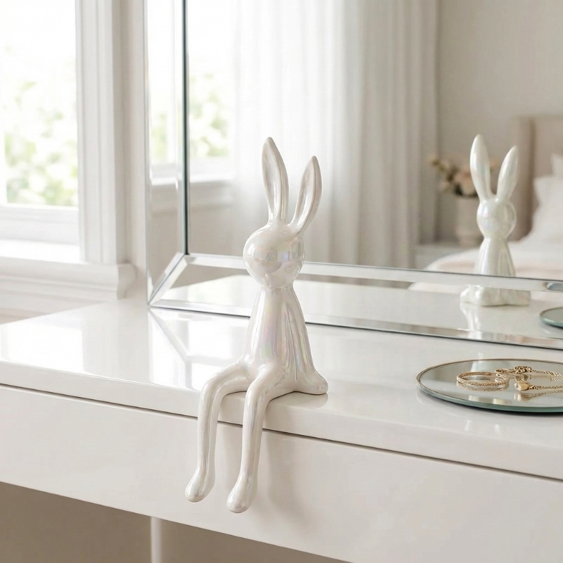White rabbit figurine on a white dresser with a mirror in the background
