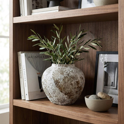 Ceramic rustic circular vase on bookshelf with plant and books