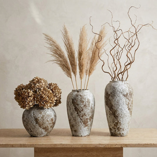 Set of ceramic rustic circular vases with dried stems on console table