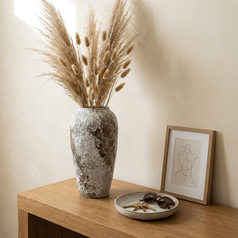 Ceramic rustic circular vase with pampas grass on wooden side table
