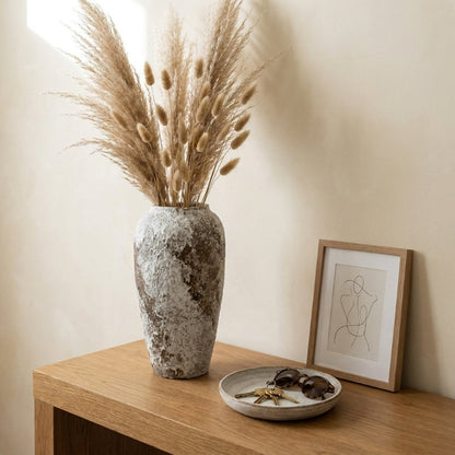 Ceramic rustic circular vase with pampas grass on wooden side table