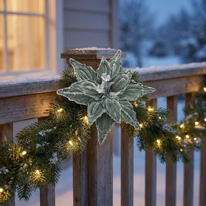 Green poinsettia flower on a snowy porch railing garland with string lights at dusk