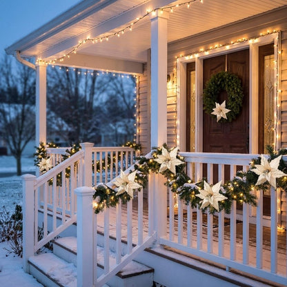 White poinsettia flowers woven into a lit garland on a porch railing at dusk