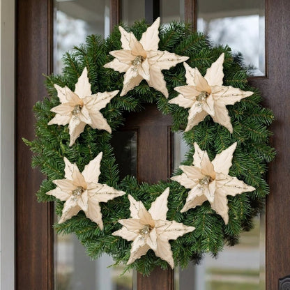 Cream-toned poinsettia flowers on a fresh pine wreath hanging on a front door