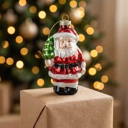 Santa ornament standing on a gift box with bokeh tree lights behind