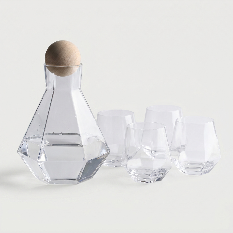 Clear glass decanter with wooden stopper and matching glasses on a light background
