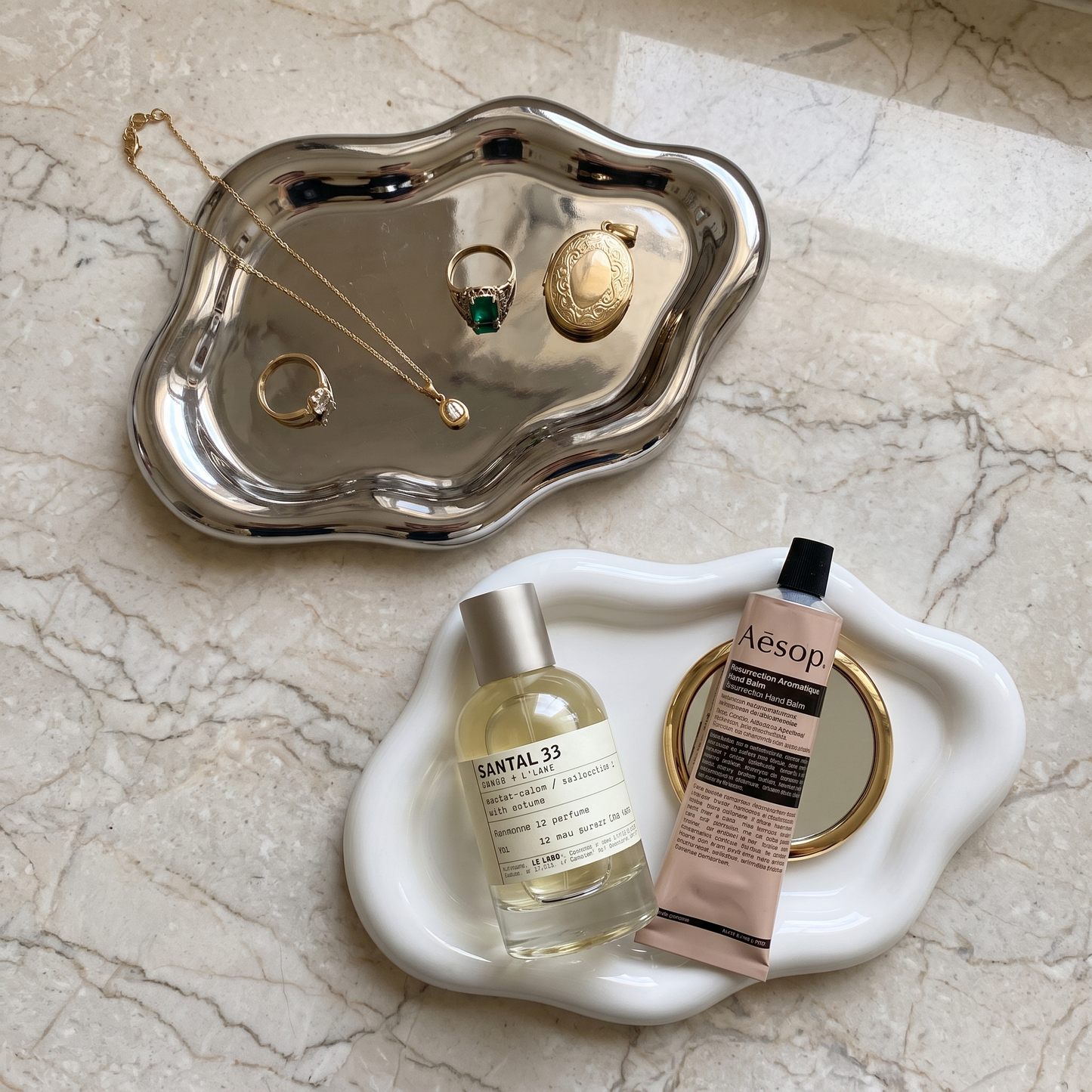 Silver cloud jewelry tray holding jewelry and perfume on marble