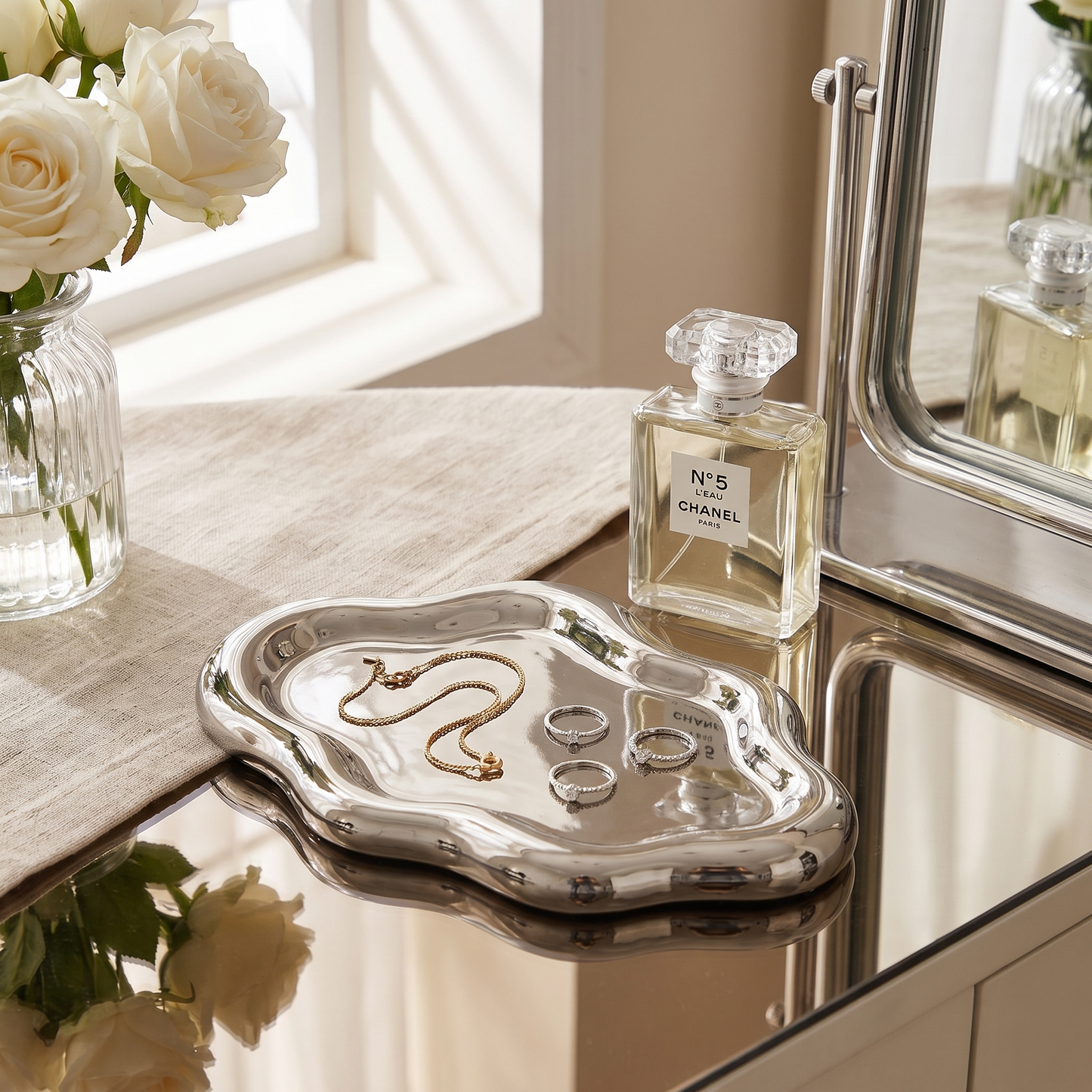 Silver cloud jewelry tray on a vanity holding rings and a necklace