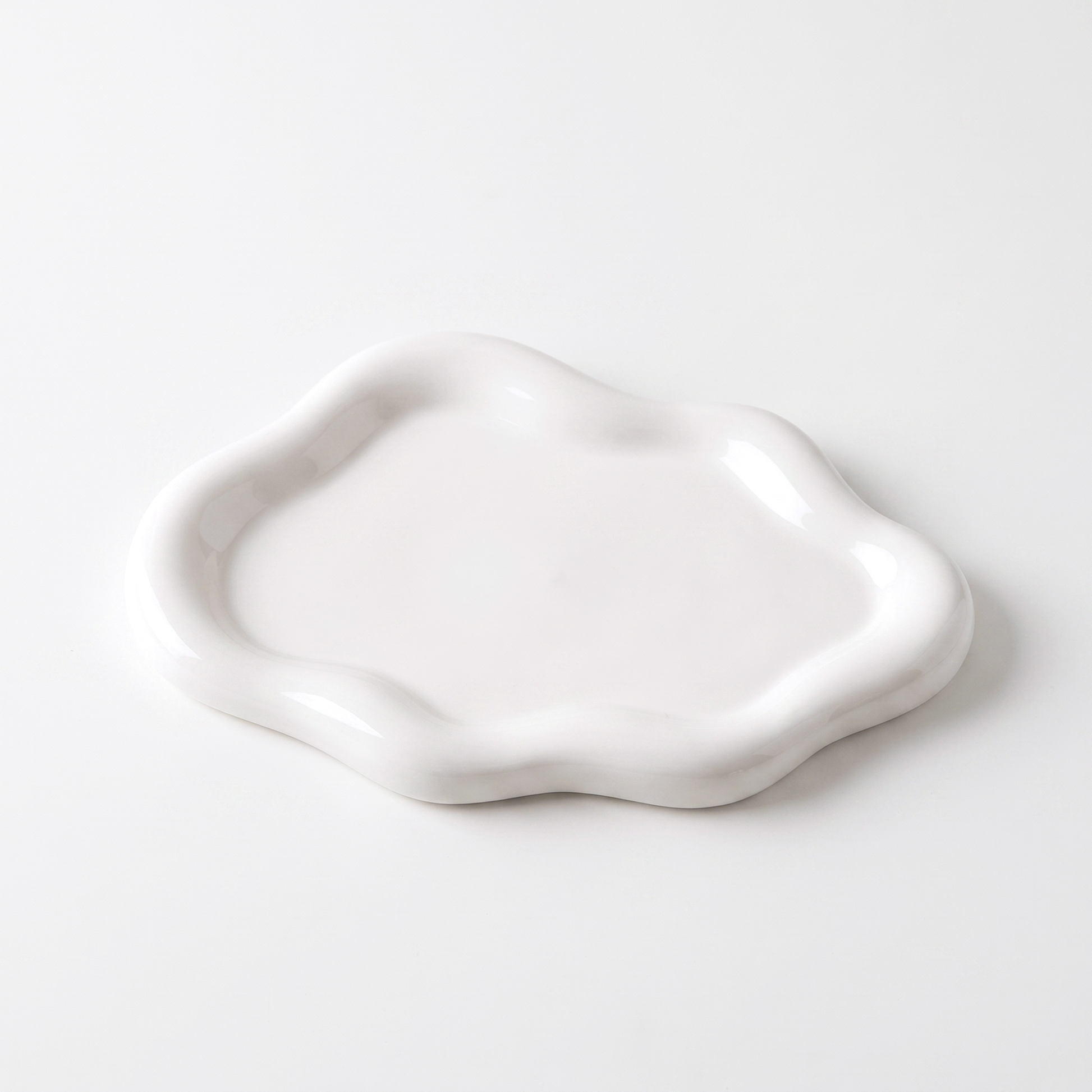 White ceramic cloud-shaped jewelry catchall on an off-white background