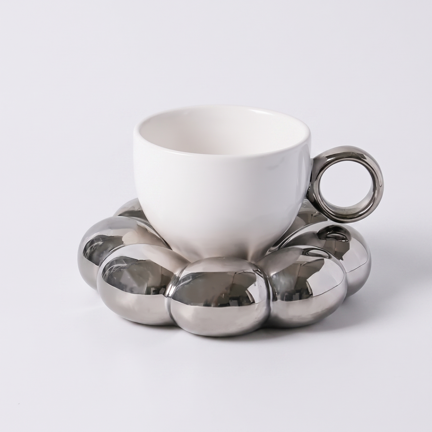 White ceramic coffee mug on a metallic silver cloud-shaped saucer, Kiyo Home cloud saucer mug set