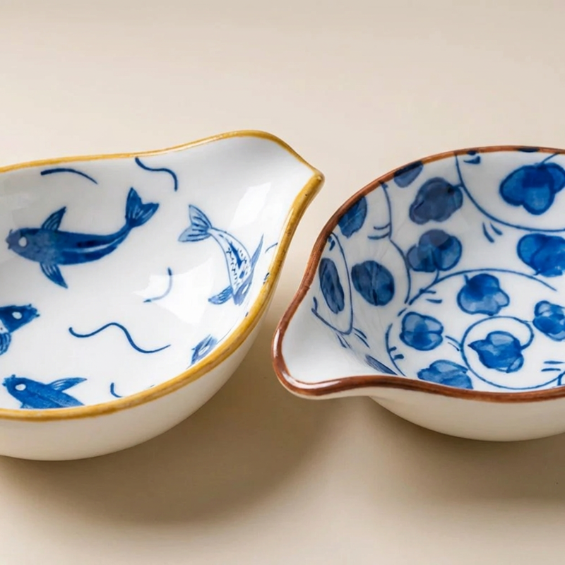 Two ceramic bowls with blue fish and floral patterns on a beige background