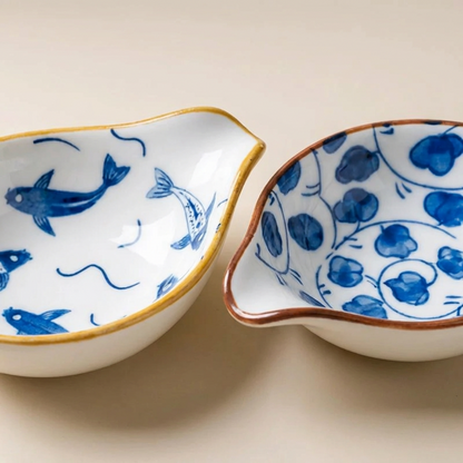 Two ceramic bowls with blue fish and floral patterns on a beige background