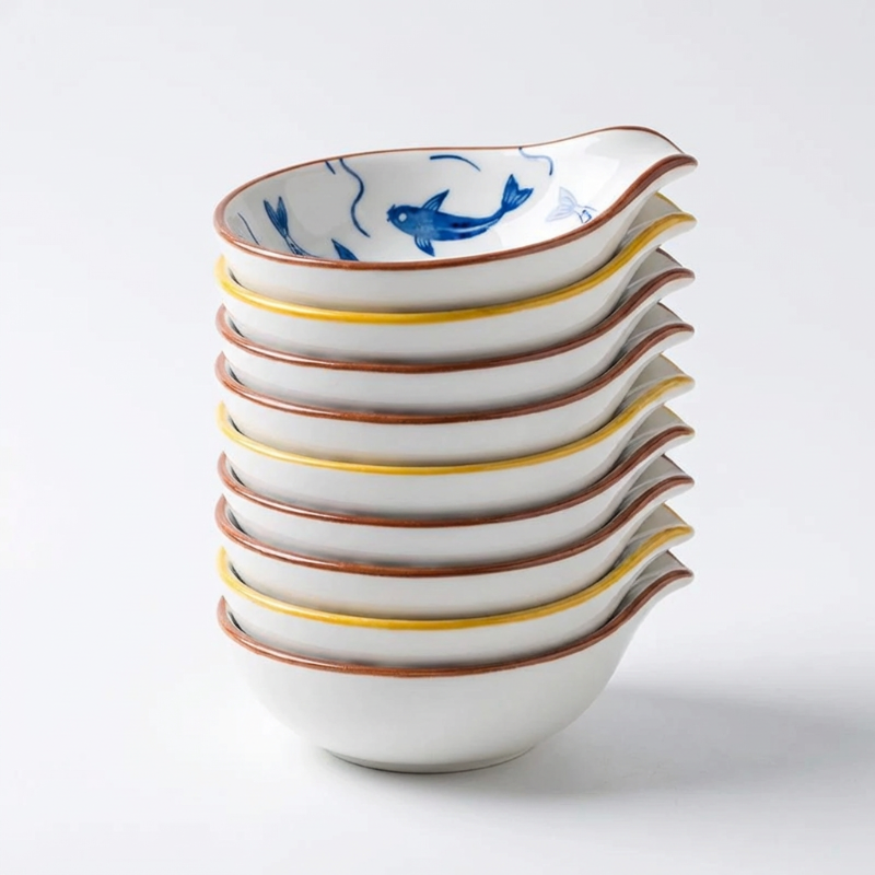 Stack of white ceramic bowls with blue and yellow accents on a light gray background