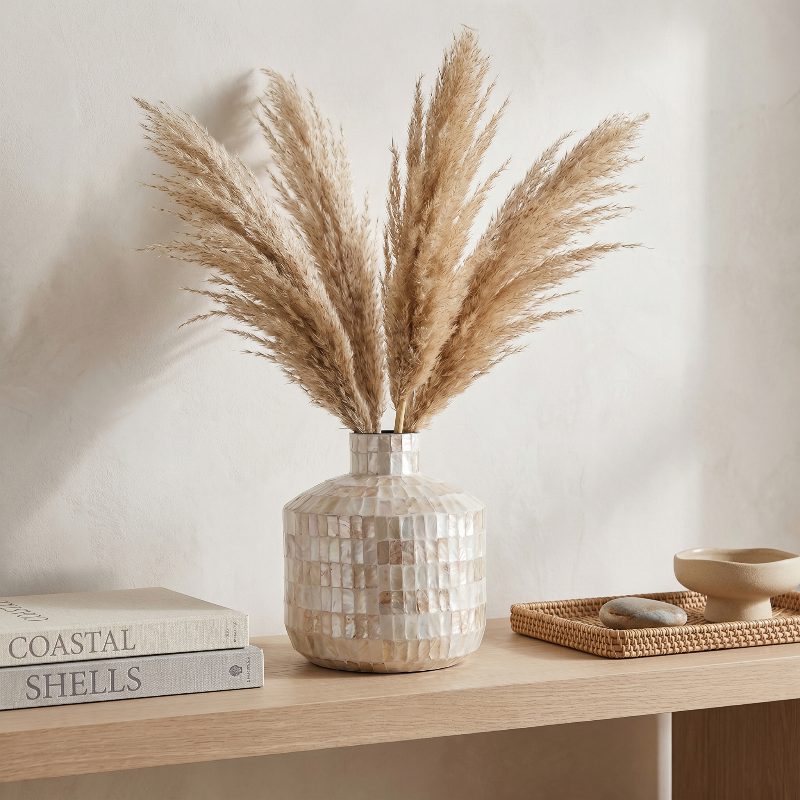 Coastal shell mosaic vase with pampas grass on wooden shelf