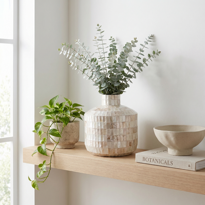 Coastal shell mosaic vase with eucalyptus stems on windowsill