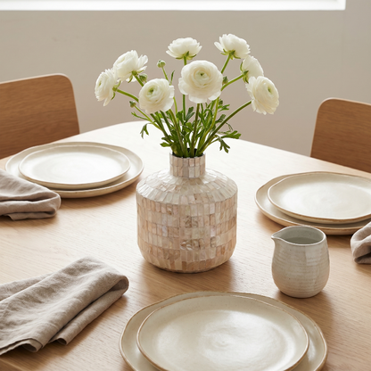 Coastal shell mosaic vase with white flowers on dining table