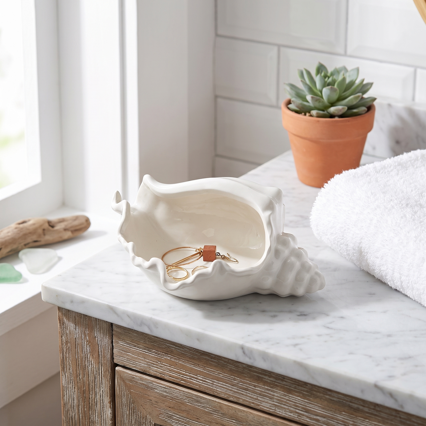White ceramic conch shell vessel on a marble bathroom counter with a succulent, Kiyo Home
