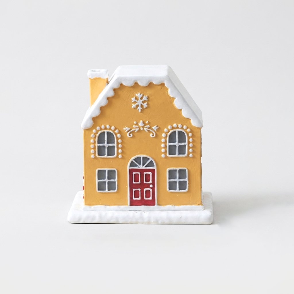 Yellow and white gingerbread-style cottage incense burner with a red door, snow-capped roof, and chimney, on a plain studio background
