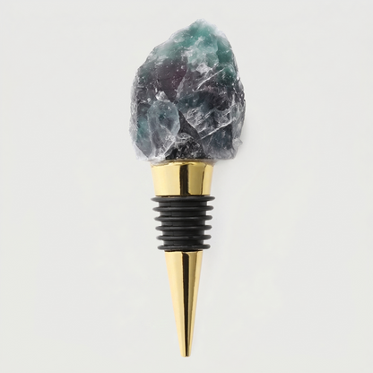 Fluorite crystal bottle stopper with gold tip on a light gray background