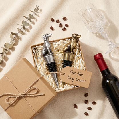 Dog wine bottle stoppers with a gift box and wine bottle on a beige surface.