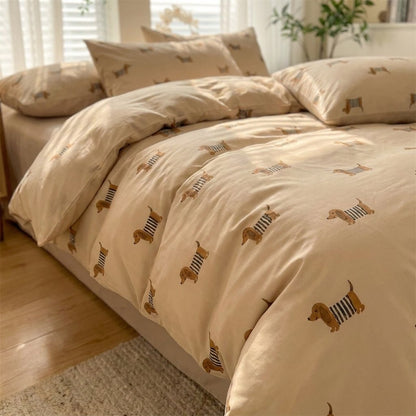 Angled close-up of a dachshund-print duvet and pillows on a bed near a sunlit window