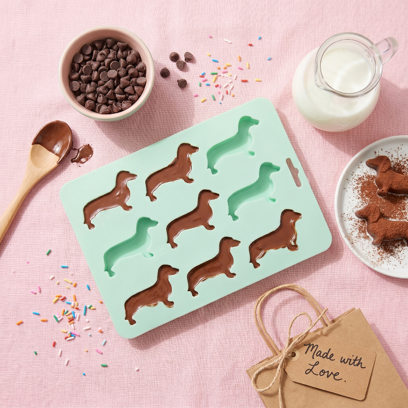 Dachshund ice cube tray on pink surface with drink ingredients