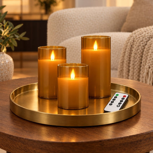 Three amber tinted flameless candles of different heights with a remote control on a round brass tray on a wood coffee table, in front of a cream sofa with a throw