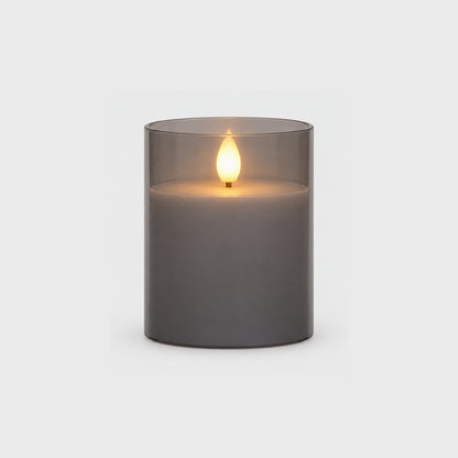 Small grey tinted flameless candle with a glowing flame on a plain light background