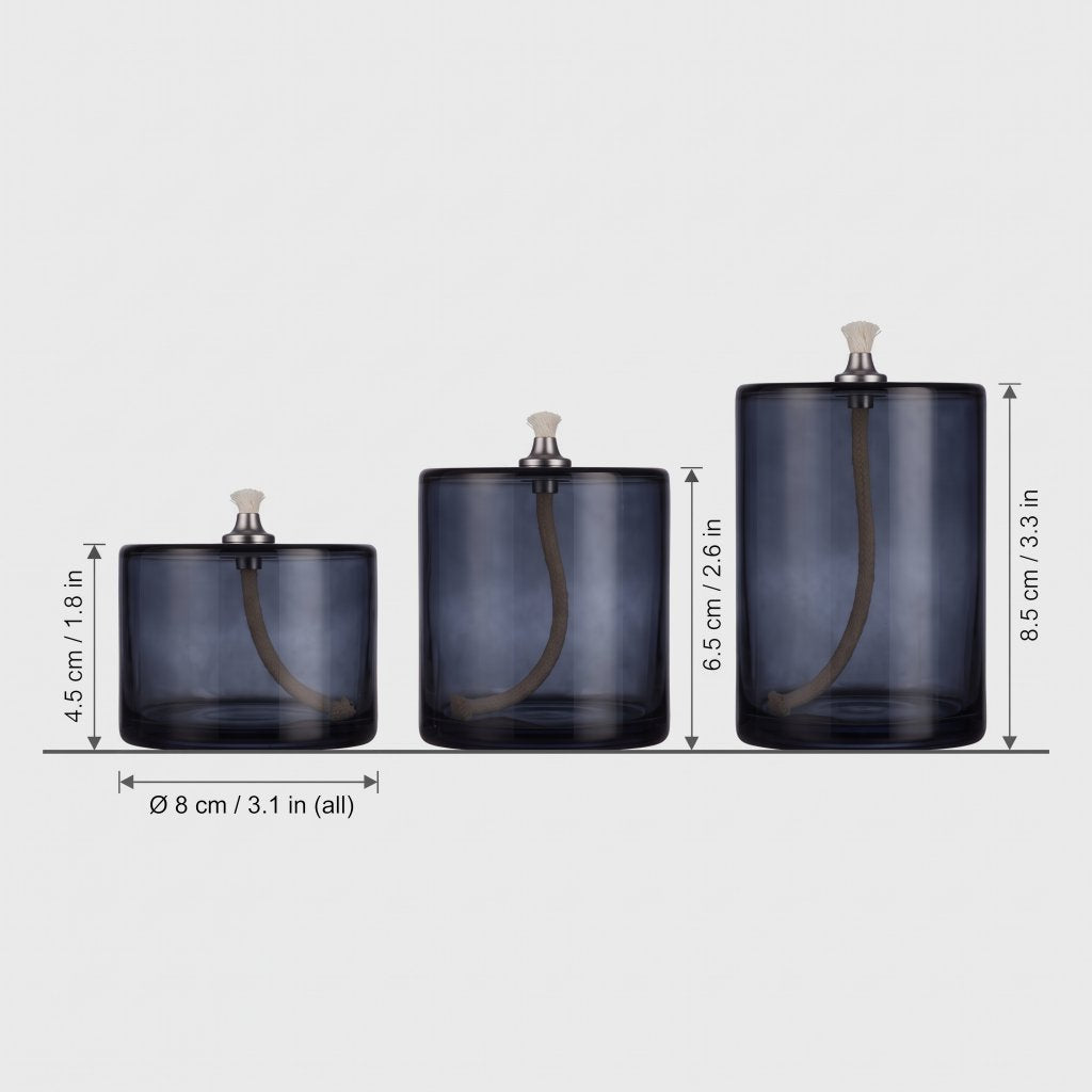 Three smoky blue-grey glass oil candles lined up by size on light grey with heights labeled 4.5 cm or 1.8 in, 6.5 cm or 2.6 in and 8.5 cm or 3.3 in and a width of 8 cm or 3.1 in for all