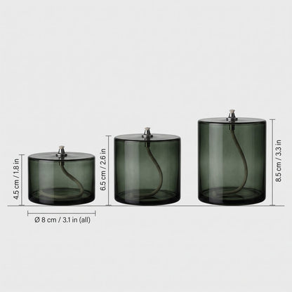 Three smoky olive green glass oil candles lined up by size on light grey with heights labeled 4.5 cm or 1.8 in, 6.5 cm or 2.6 in and 8.5 cm or 3.3 in and a width of 8 cm or 3.1 in for all