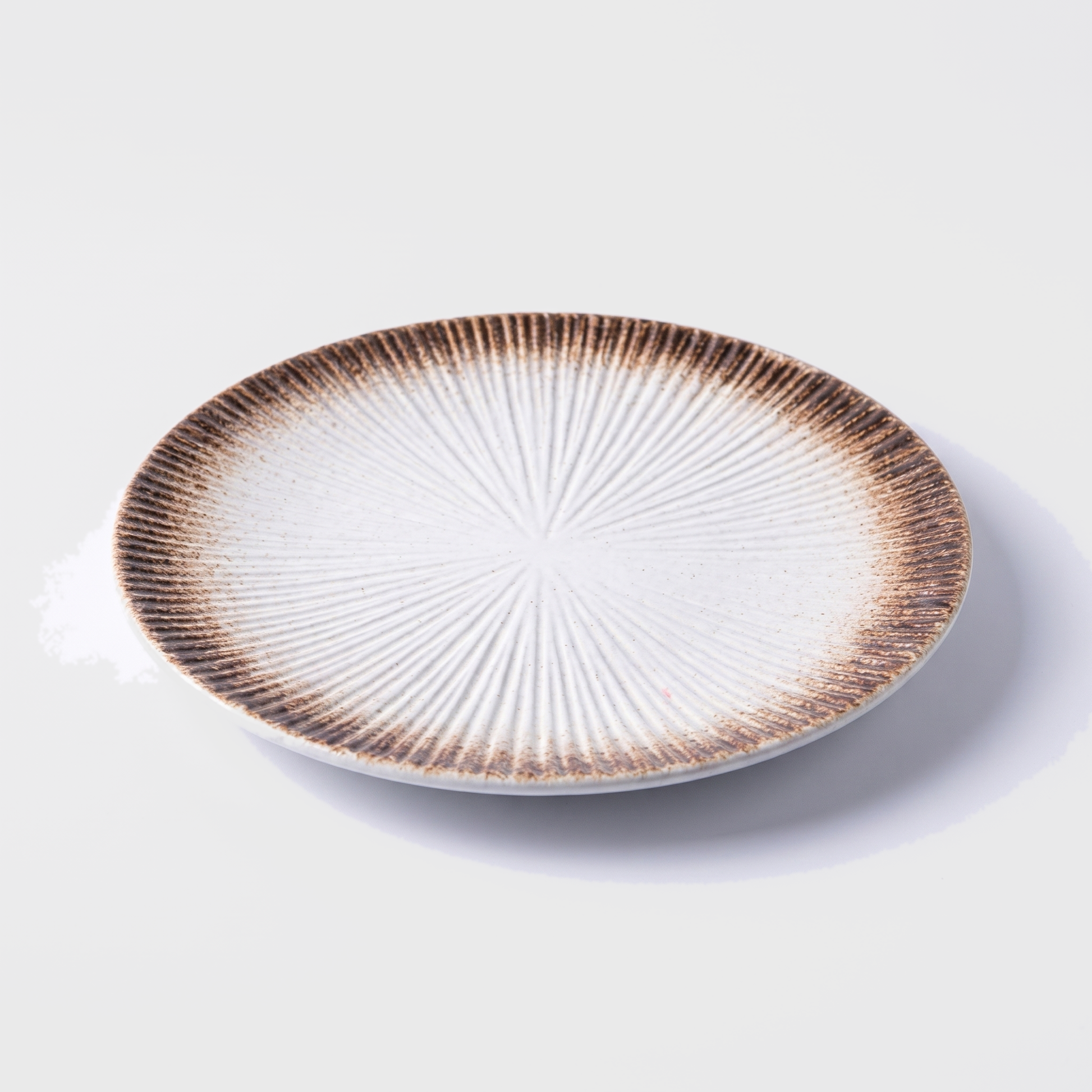 Brown disc ceramic dinner plate with radial ridged design on an off-white background