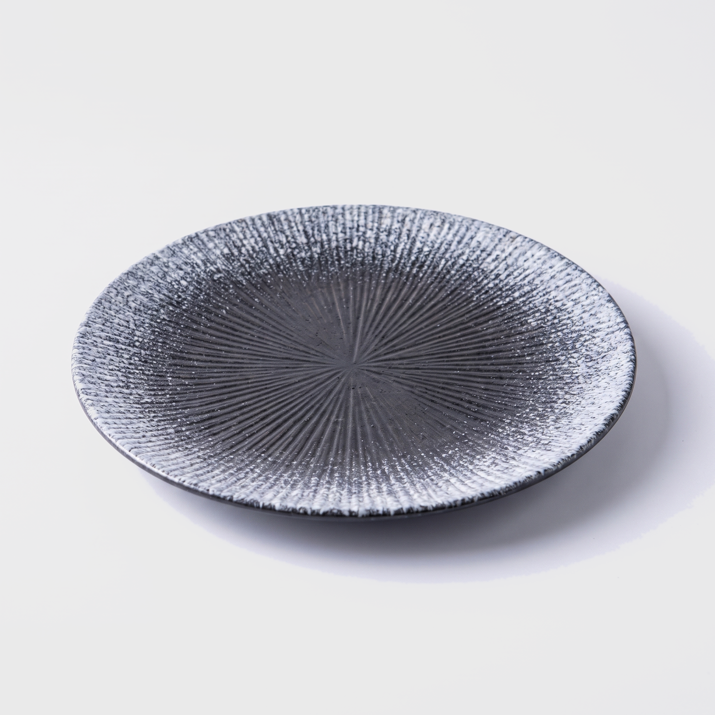Gray disc ceramic dinner plate with radial ridged design on an off-white background