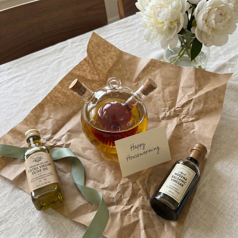Dual oil and vinegar bottles on kitchen table with bread and herbs