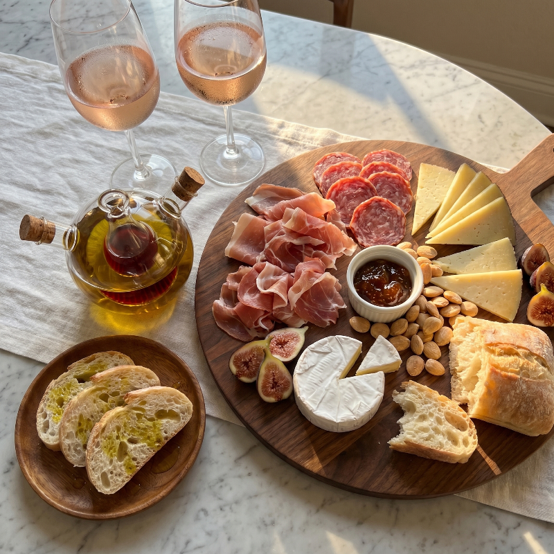 Dual oil and vinegar bottles on charcuterie board with snacks