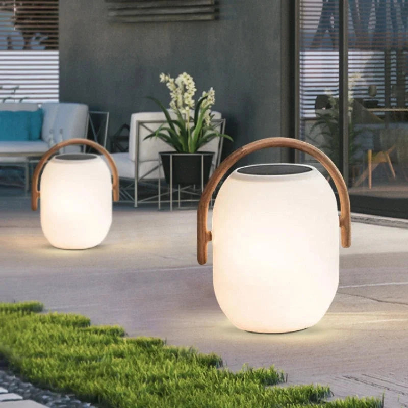 Two illuminated outdoor lamps with wooden handles on a patio.