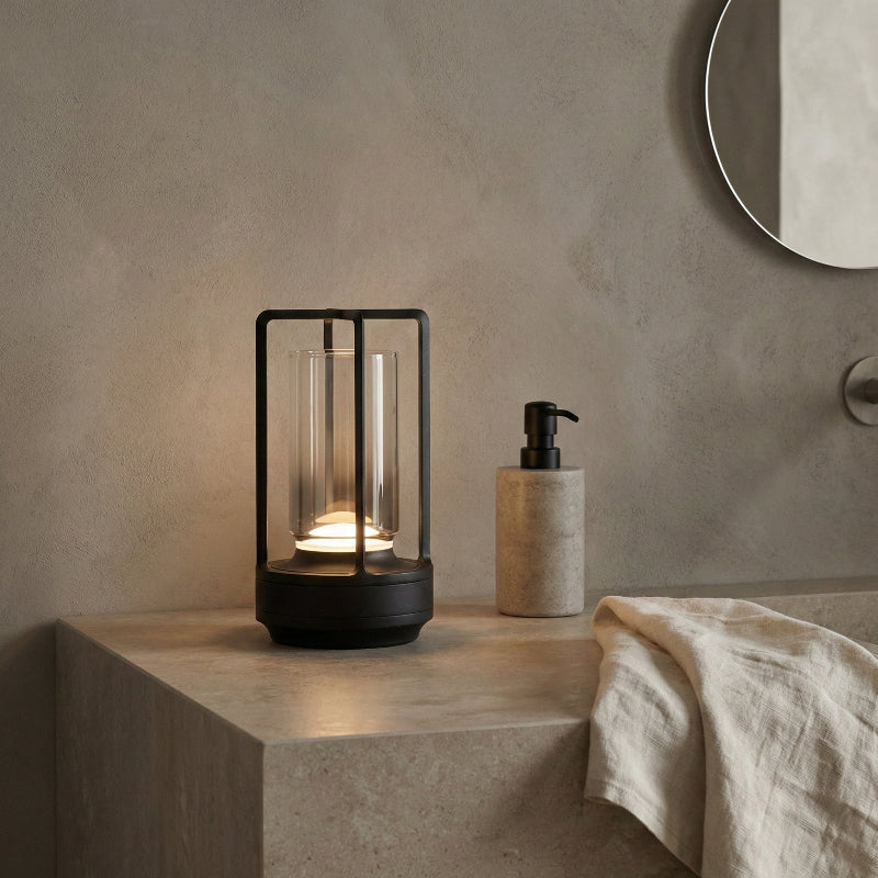 Modern black lantern-style lamp on a concrete surface with a neutral background