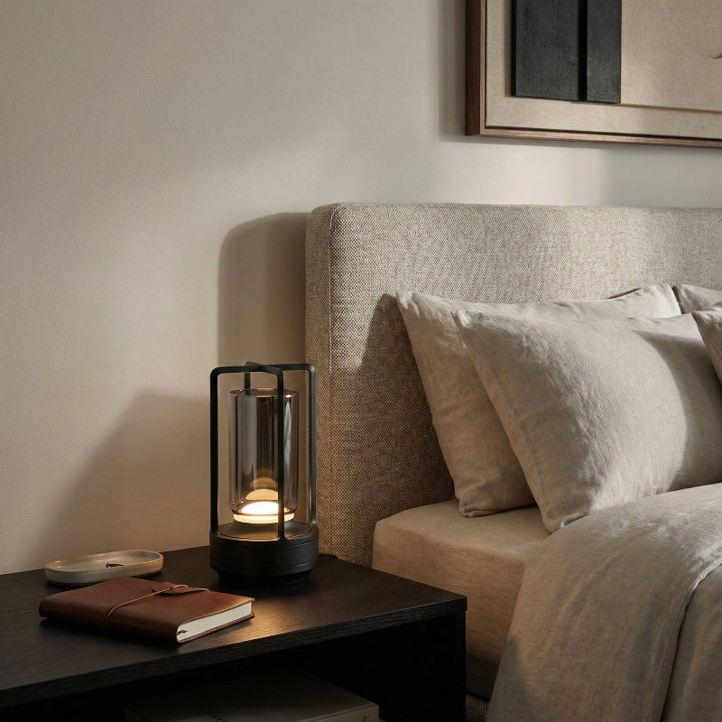 Lantern on a nightstand next to a bed with pillows