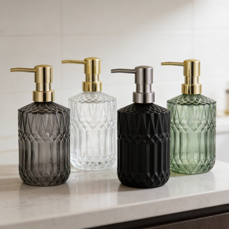 Facet glass soap dispensers in black, smoke, and green on white counter