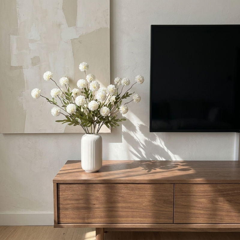 White faux dandelion stems in white vase on media console