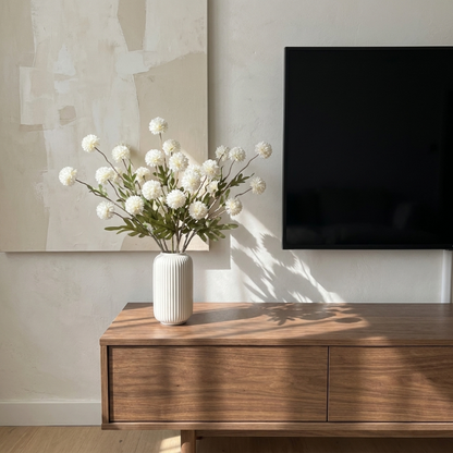 White faux dandelion stems in white vase on media console