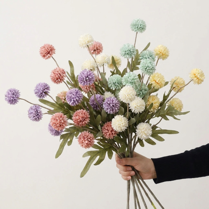 Faux dandelion stems in multicolor bouquet held in hand