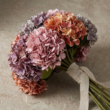 Bouquet of hydrangeas in pink, purple, and orange on a textured surface