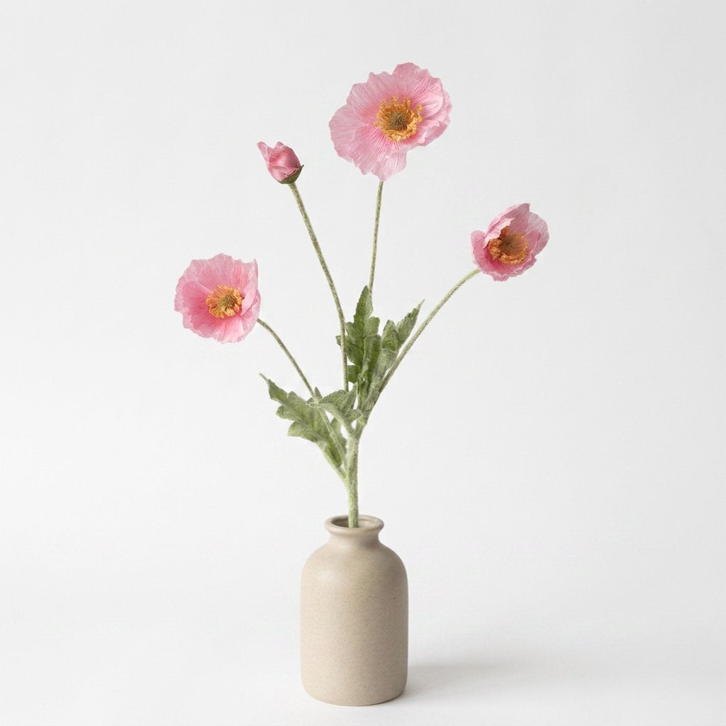Four faux poppy stems with three medium rose-pink blooms and a deeper pink bud in a speckled oatmeal ceramic jar on a plain light backdrop