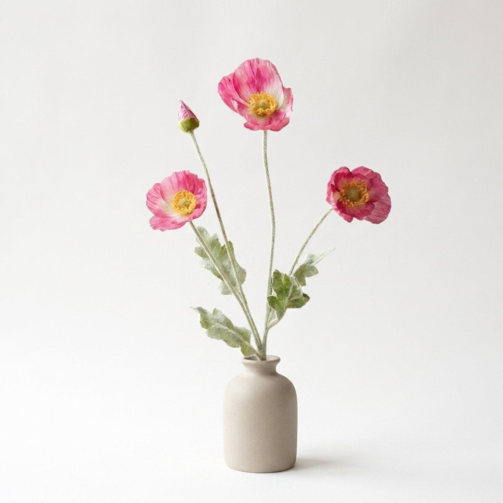 Four faux poppy stems with three two-tone pink blooms, deeper pink at the edges, and a pink bud in a matte cream ceramic bottle vase on a plain light backdrop