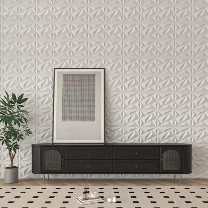 A modern living room featuring a white geometric accent wall, a black media console with framed art above it, a potted plant, and a patterned rug.
