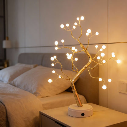 Decorative LED tree on a nightstand with a bed in the background