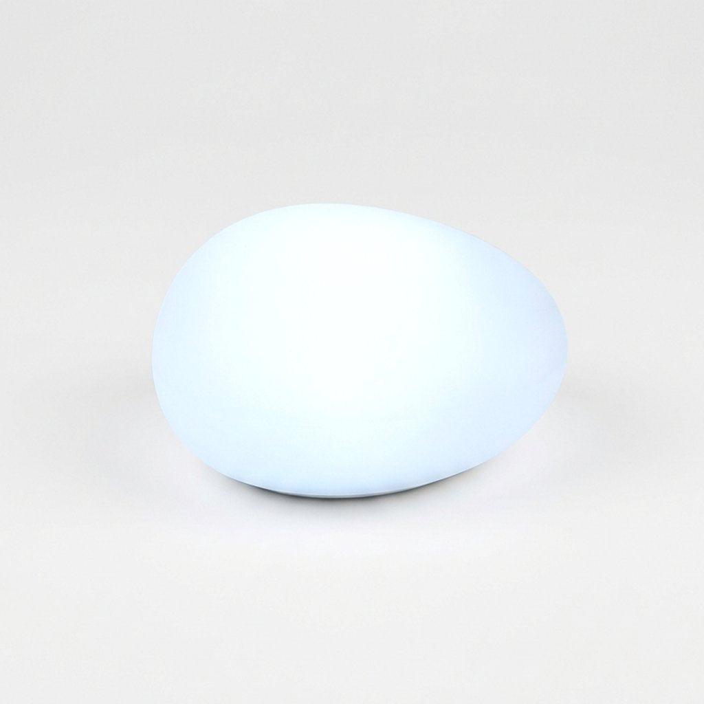 One frosted solar glass pebble light glowing cool white on a light background