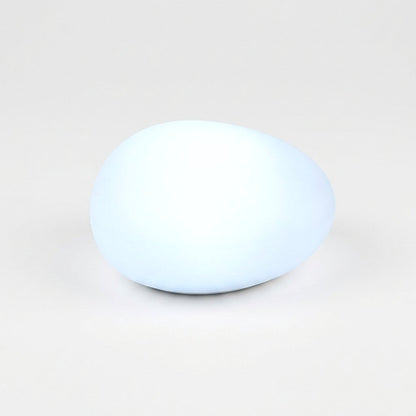 One frosted solar glass pebble light glowing cool white on a light background