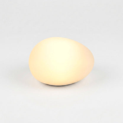One frosted solar glass pebble light glowing warm yellow on a light background